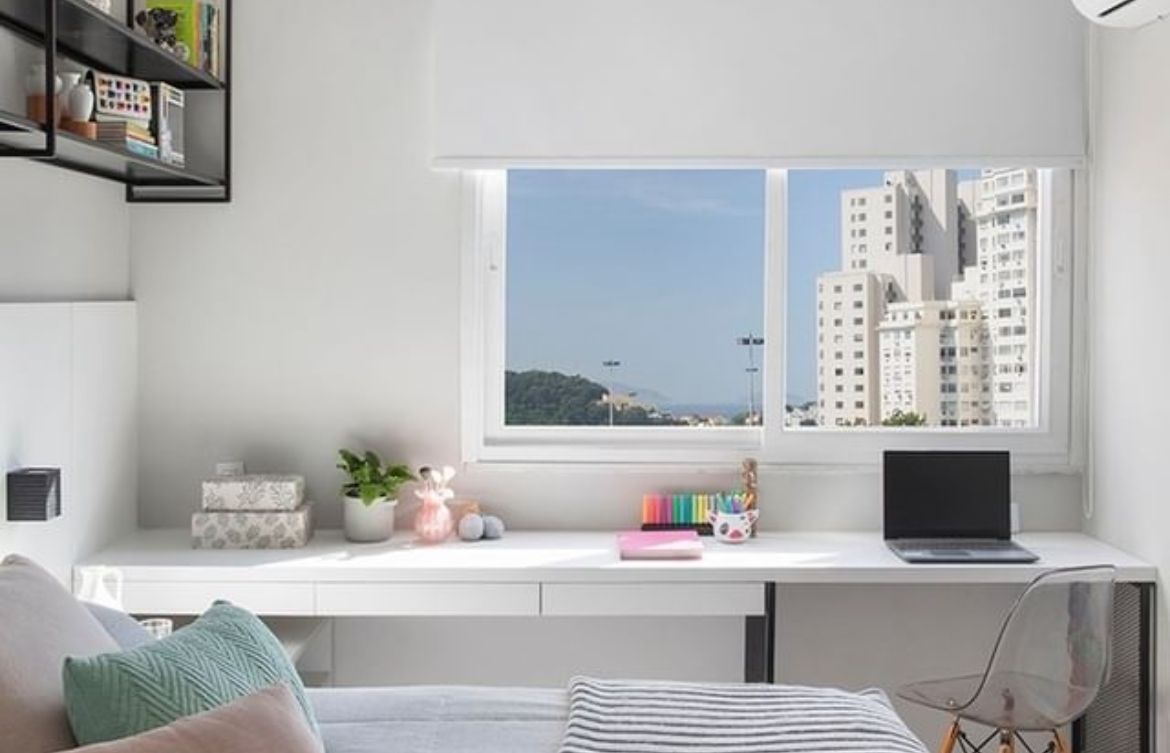 Quarto com janela grande, escrivaninha branca e ambiente silencioso, mostrando qualidade sonora.